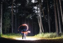 How to Cast a Love Spell That Actually Works A mysterious figure creates light trails in a dark forest at night, evoking magic and mystery. - cast a love spell