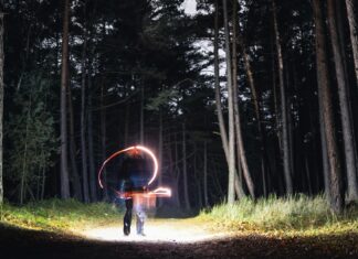 How to Cast a Love Spell That Actually Works A mysterious figure creates light trails in a dark forest at night, evoking magic and mystery. - cast a love spell