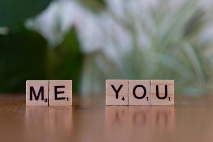 Close-up of Scrabble tiles spelling 'Me You' symbolizing love and connection on a wooden table. - how to know if someone put a love spell on you