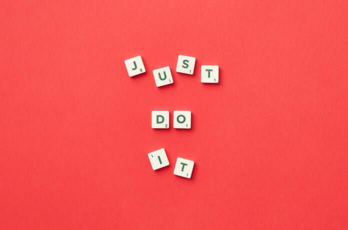 Motivational phrase 'Just Do It' spelled with Scrabble letters on a red background. - love spells that work overnight with just words