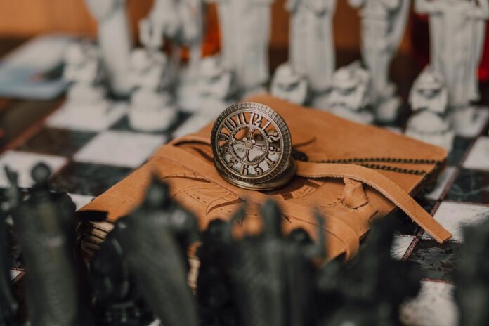 A steampunk clock rests on a leather-bound notebook with chess pieces in the background, evoking a magical atmosphere. - binding love spells