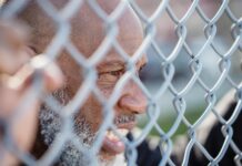 Powerful Obsession Spells That Really Work Close-up of mature man behind a metal fence, conveying deep thought and emotion. - obsession spells