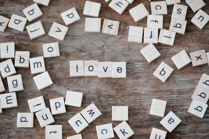 Scrabble tiles spelling 'love' on a rustic wooden surface, offering a charming and playful aesthetic.