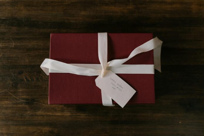 Red gift box with white ribbon and handwritten tag on rustic wooden background. - how to make my ex miss me desperately